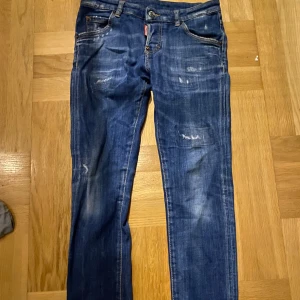 Blå jeans från Dsquared2 - Säljer ett par snygga blå jeans från Dsquared2 i storlek 14Y. De har en cool slitningseffekt och klassisk femficksdesign. Perfekta för en avslappnad stil med en touch av edge. Passar både till vardags och festliga tillfällen. Passformen är slim fit kan även tänka mig byta mot en Moncler cardigan, 10/10 skick inga skador på Byxorna! Mvh Charlie!🤝