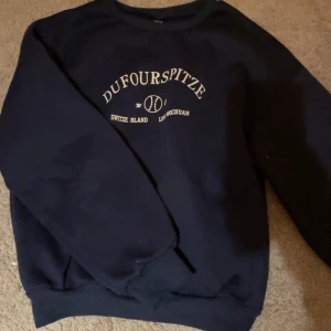 Mörkblå sweatshirt med tryck - Säljer en mörkblå sweatshirt med tryck 'Dufourspitze' i vitt. Tröjan är i bra skick. Den har långa ärmar och en rund halsringning💙