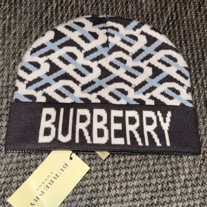 Mönstrad mössa från Burberry - Snygg mössa från Burberry med ett unikt mönster i svart, blått och vitt. Tillverkad i 100% bomull, perfekt för att hålla stilen i kallare väder. Den har en bred kant med Burberry-loggan i vitt.