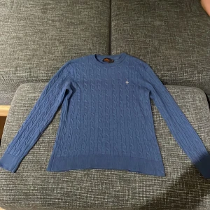 Blå stickad tröja - Säljer en snygg blå stickad tröja med kabelstickat mönster. Tröjan har långa ärmar och en rund halsringning. Perfekt för kyliga dagar och passar både till vardags och lite finare tillfällen. Supermysig och stilren! Pris går alltid att förhandlas!