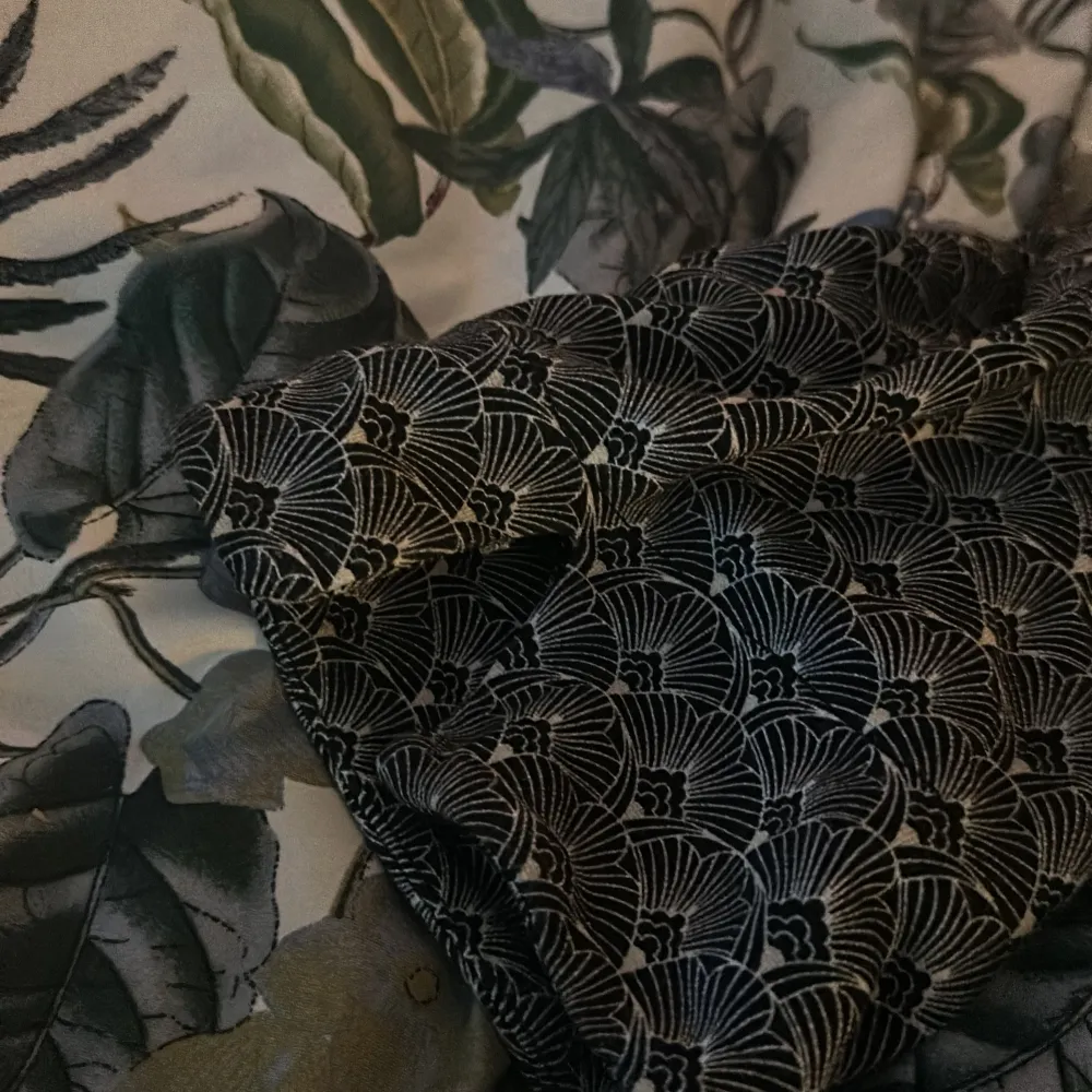 Säljer en svart topp från KappAhl med ett elegant mönster i vitt. Toppen har trekvartsärmar och en v-ringad hals. . Puserot.