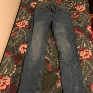 Blå jeans - Säljer ett par klassiska blå jeans i bra skick. De har en normal passform och är perfekta för vardagsbruk. Jeansen har en traditionell femficksdesign och stängs med dragkedja och knapp. Perfekta för både höst och vår!