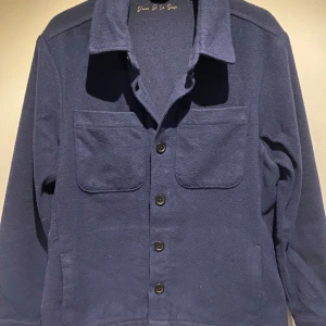 Mörkblå overshirt från D’once de la sense - Säljer en snygg mörkblå overshirt från D’once de la sense. Den är knappt använd och är tvär snygg. Ny pris: 1500kr jag säljer den för 900. Perfekt för höst och vår, och funkar både till vardags och fest. 