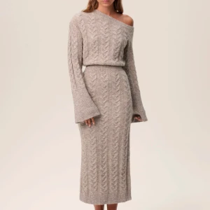 Adoore stickad klänning - Helt ny med alla prislappar kvar. Den är helt slutsålda. Beige stickad klänning från Adoore med offshoulder-design och långa ärmar. 