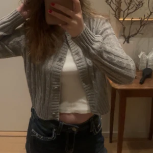 Grå och brun ribbad kofta - Två ribbade koftor i grått och brunt. Båda har knappar framtill och långa ärmar. 