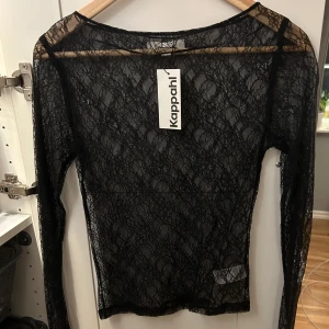 Svart spetstopp från Kappahl - Snygg svart spetstopp från Kappahl med långa ärmar. Perfekt för en elegant look med sitt genomskinliga spetsmaterial. Passar utmärkt till både fest eller nyår för en stilren outfit. Väldigt populär och säljs inte längre. Aldrig använd helt ny med prislapp❤️