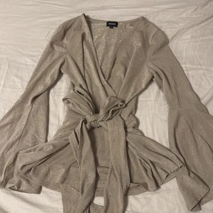 Glittrig topp - Säljer en superfin glittrig topp från bubbleroom i storlek M. beige färg. Aldrig använd. Ser längre ut än vad den är på bilden