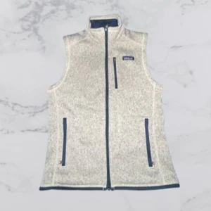 Grå fleeceväst från Patagonia - Snygg och praktisk grå fleeceväst från Patagonia med dragkedja framtill och två fickor med dragkedjor. Perfekt för lager-på-lager under kyliga dagar.