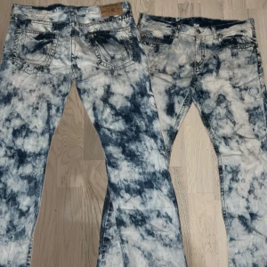 Bleached True Religion Jeans - Säljer ett par unika jeans från True Religion med ett coolt mönster i blått och vitt. De har en straight passform och är perfekta för dig som vill sticka ut. Jeansen har klassiska fem fickor och en knappgylf.