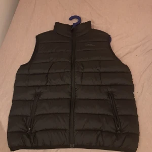 Svart väst  Kappahl - ‼️OBS PRIS KAN DISKUTERAS                    Säljer en svart väst från Kappahl med dragkedja framtill. Storleken motsvarar "Medium".    Västen har en stilren design och är perfekt för kyligare dagar. Den är märkt med 'Premium Youth Style' och har praktiska fickor med dragkedja. 