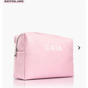 Rosa necessär från CAIA - Säljer en söt rosa necessär från CAIA med dragkedja. Perfekt för att förvara smink eller andra småsaker. Enkel och stilren design med CAIA-logga på framsidan. Ingår även 3 läppenor varav en ifrån Caia. Observera att det finns fläckar inuti.
