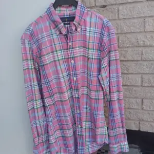 Säljer en snygg rutig skjorta från Ralph Lauren i en härlig mix av rosa, blå, grön och vit. Skjortan har en klassisk krage och knappar framtill. Den är i slim fit och har långa ärmar, perfekt för både vardag och fest! superfint skick. nypris 1799kr