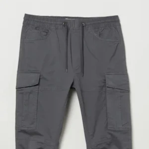 Svarta cargopants från H&M - Säljer ett par svarta cargopants från H&M i storlek S. Byxorna har en slim fit passform och är utrustade med praktiska fickor på sidorna. De har en elastisk midja med snörning för extra komfort. Perfekta för en casual look!