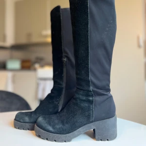 Stövlar  - Höga stövlar i äkta mocka med stretchigt konstmaterial baktill för en tight passform. I fint skick, har använt ställning till skorna för att dom inte ska ”säcka ihop” mellan användning. Storlek 37. Minns inte inköpspris exakt men mellan 1000-1500 kr.