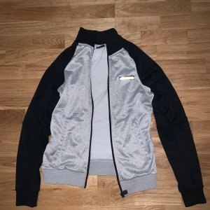 Grå och svart jacka från Ellesse - Säljer en snygg grå och svart kofta från Ellesse. Den har logo på bröstet och logo på armarna. Perfekt för en casual look. Jackan är i bra skick och knappt använd. Priset kan diskuteras