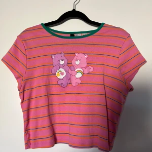 Randig T-shirt - Rosa T-shirt med gröna och orangea ränder + motiv av krambjörnar på framsidan Använd vid 2 tillfällen, nära nyskick
