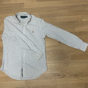 Ralph Lauren ”Oxford” Skjorta - En mycket fin ”Oxford” skjorta från Ralph Lauren. Den är i extremt bra skick och extremt bra kvalitet (100% bomull). Modellen är 183cm och väger 75kg. Vid eventuella funderingar så är det bara att kontakta oss!