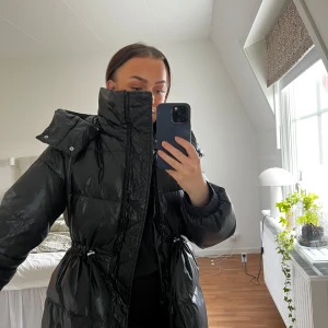 Pufferjacket från Kappahl  - Snygg jacka från Kappahl som är helt slutsåld. Använd fåtal gånger, är i väldigt fint skick. Är en Xs. Själv använder jag vanligtvis XS och S och är 156cm lång. Glansig med spänne i midjan som går att justera.