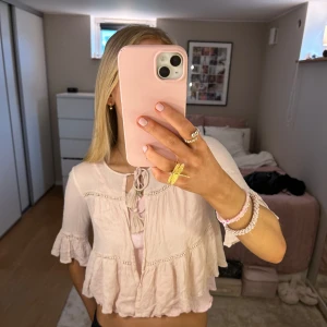 Ljusrosa blus med volanger - Säljer en superfin ljusrosa blus med volanger och knytning framtill. Blusen har trekvartsärmar och är perfekt för vår och sommar. Den är i mycket bra skick och ger en romantisk och bohemisk känsla. Passar perfekt till både jeans och kjol!