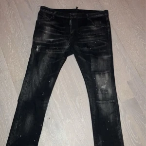 Svarta jeans med slitningar från DSQ2 - Säljer ett par svarta jeans från DSQ2 i bra skick. De har coola slitningar och en unik tvättad look. Perfekta för en avslappnad stil med en edgy touch. Passar både till vardags och fest!