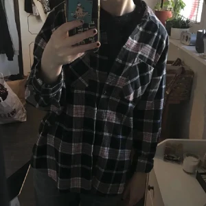 Rutig skjorta i svart och rosa - Säljer en superfin rutig skjorta i svart och rosa. Den har en avslappnad passform och långa ärmar, perfekt för höst och vår. Skjortan är i bra skick och passar både till vardags och fest. Ett måste i garderoben för den som älskar rutigt! 💖