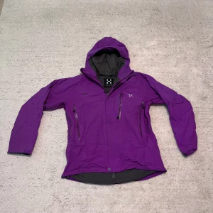 Haglöfs jacka - Säljer en snygg lila jacka från Haglöfs i storlek L för damer. Jackan har en praktisk huva och flera dragkedjefickor. Perfekt för utomhusaktiviteter under höst och vår. Den är i mycket bra skick och redo för nya äventyr!