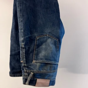 Acne jeans - Säljer ett par snygga blå jeans från Acne i bra skick. De har en klassisk design med en praktisk ficka på sidan och en läderpatch med Acne Jeans-loggan baktill. Perfekta för både vardag och fest!
