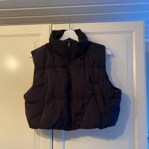 Svart väst - Säljer en svart väst i mycket bra skick. Den har en dragkedja framtill och en hög krage för extra värme. Perfekt för höst och vinter när du vill hålla dig varm utan att bära en tung jacka. Passar bra till både vardag och utomhusaktiviteter.