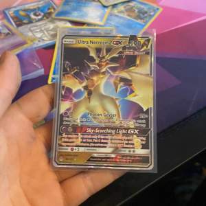 En Ultra Necrozma GX Pokémon-kort i mint condition. Kortet har en holografisk yta med en kraftfull design av Ultra Beast. Perfekt för samlare eller spelare som vill förstärka sin kortlek. Ny pris 80-100kr