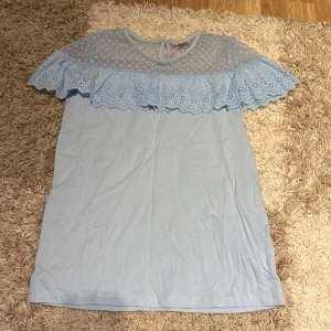 Ljusblå topp med spetsdetaljer från LC Waikiki - Säljer en söt ljusblå topp från LC Waikiki. Den har vackra spetsdetaljer och volang runt axlarna. Perfekt för vår och sommar! Toppen är i mycket bra skick och passar både till vardags och festligare tillfällen.