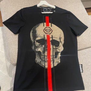 Svart t-shirt med dödskalle från Philipp Plein - Säljer en svart t-shirt från Philipp Plein. Den är i mycket bra skick och knappt använd! Stl L men den är liten i stl så passar stl M