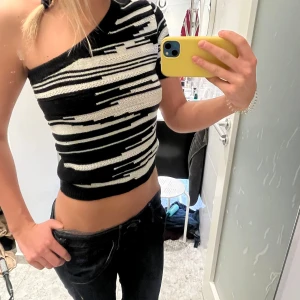 Svart och vit randig oneshoulder topp - Snygg och trendig oneshoulder topp i svart och vitt med randigt mönster. Perfekt för en utekväll eller fest! Toppen är croppad och har en tight passform som framhäver figuren. Storlek XS från Lindex 