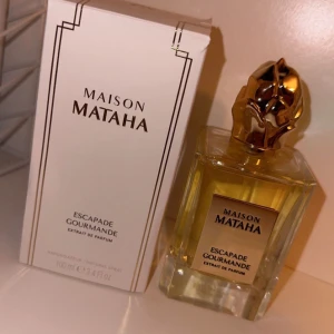 Maison Mataha Escapade Gourmande Extrait de Parfum - Lyxig parfym från Maison Mataha i en elegant fyrkantig flaska med en gyllene kork. Doften 'Escapade Gourmande' är en extrait de parfum, vilket betyder att den har en hög koncentration av doftoljor. Förpackningen är stilren och vit med subtila svarta detaljer. Perfekt för den som älskar exklusiva och långvariga dofter. Ordinarie pris 2290. 