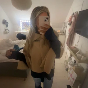 Beige poncho - Säljer en superfin poncho i beige. Perfekt för höst och vår, med en loose passform som gör den både bekväm och stilren. Den ärmlösa designen gör den lätt att bära över en tröja eller blus. Perfekt för att hålla sig varm och snygg under kyligare dagar!