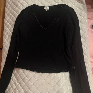 Svart långärmad tröja från Calvin Klein - Säljer en svart långärmad tröja från Calvin Klein med v-ringning. Tröjan har ett coolt paljettmönster på baksidan som stavar 'CALVIN'. Perfekt för höst och vinter, och den är i bra skick. Passar både till vardags och fest!