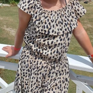 Leopardmönstrad byxdress för barn - Söt leopardmönstrad byxdress för barn med volangdetaljer och korta ärmar. Perfekt för sommarens äventyr och lek. Byxdressen har en bekväm passform och är gjord i ett lätt material som passar bra för varma dagar.