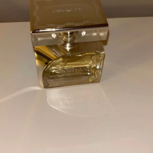 Versace Vanitas parfym - Säljer en helt ny bara utan förpackning elegant Versace Vanitas parfym i en stilren glasflaska med en lyxig, fyrkantig design. Flaskan har en genomskinlig guldfärgad vätska och ett snyggt silverlock. Perfekt för den som vill ha en sofistikerad doft på hyllan. Passar både till vardags och fest!