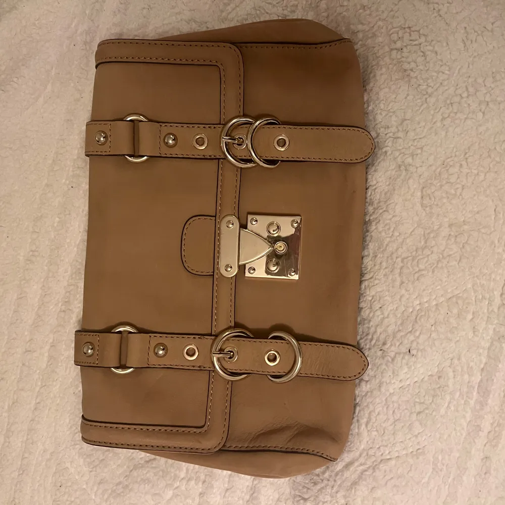 Säljer en snygg beige axelväska från Reiss i mycket bra skick. Väskan är gjord av skinn och har en stilren design med guldiga metallspännen. Perfekt för både vardag och fest! 👜✨Lägg gärna prisförslag!. Väskor.