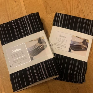 Svart- och vitrandiga servetter - Säljer ett set med fyra stiliga servetter i svart med vita ränder. De är 40 x 40 cm stora och gjorda av 60% bomull, 33% polyester, 4% metalliskt garn och 3% viskos. Perfekta för att ge en elegant touch till middagsbordet. Passar både till vardag och fest!