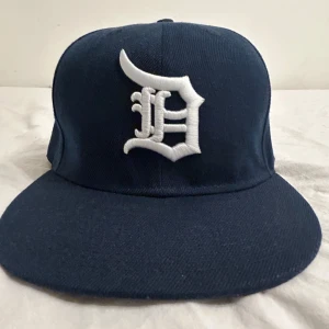 Mörkblå keps new era  - Snygg mörkblå keps från New Era med en vit broderad logga på framsidan. Kepsen har en klassisk design med platt skärm och är i mycket bra skick. Storlek 56,8 CM 