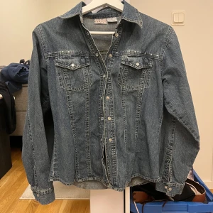 Jeansjacka i blå denim - Säljer en jeansskjorta i denim, med coola detaljer på ryggen och fram