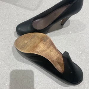 Tamaris skor  - Snygga svarta tamaris i äkta läder med en elegant klack. Perfekta för både fest och mer formella tillfällen. De har en klassisk design med spetsig tå och är i mycket bra skick. Passar perfekt till en chic outfit!