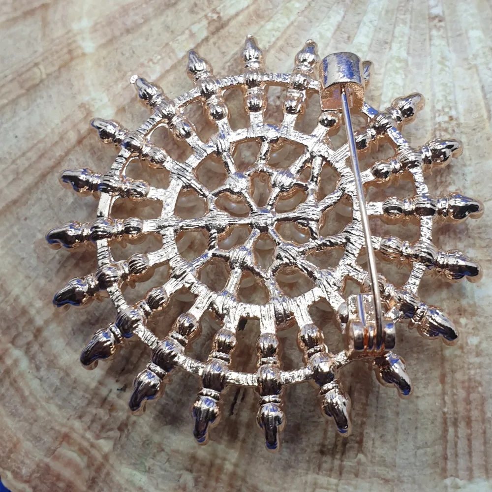Den här broschen föreställer en Kristallbrosch och måtten är ca 5×5 cm. Roseguldfärgad metall med vacker ytstruktur och ytan täckt av kristaller och pärlor. Otroligt vacker brosch.. Asusteet.