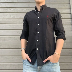 Svart Polo Ralph Lauren Skjorta - Hej! Säljer en Polo Ralph Lauren skjorta i nyskick. Priset kan diskuteras vid snabb affär!