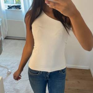 Säljer en stilren vit oneshoulder topp. Perfekt för sommardagar eller en utekväll. Toppen är tight och framhäver figuren snyggt❤️