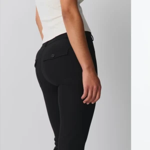 Lågmidjade bootcut kostymbyxor - Snygga bootcut kostymbyxor med låg midja från gina. Knappar bak på fickorna och en jättefin passform, perfekta för både vardag och fest men passar ej mig därav säljs dem. Endast använd 1 gång💕