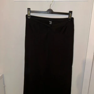 Svart kjol från Shein - Säljer en elegant svart långkjol från Shein i storlek L. Kjolen har en stilren design med en diskret slits på sidan som ger en snygg detalj. Perfekt för både vardag och fest!