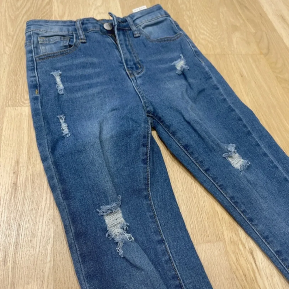 Säljer ett par snygga blå jeans med slitningar. De har en hög midja och en skinny passform som sitter riktigt bra. Perfekta för en casual look! . Jeans & Byxor.