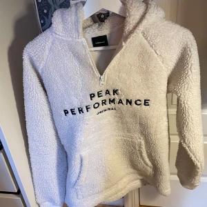 En jättefin vit, fluffig hoodie från Peak Perfomance! - Storleken är 160 och är i bra skick.