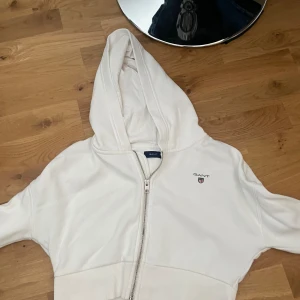 Gant tröja - vit gant tröja med dragkedja och luva. den är också som en magtröja, den är jätte snygg med ett linne under. som ni ser är den i storlek 146/152 men den är fortfarande lång i armarna så andra storlekar skulle också kunna ha den.  köpte tröjan för 900